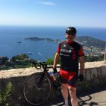 A Cyclist in Black and Red by the Side of a Stone Wall