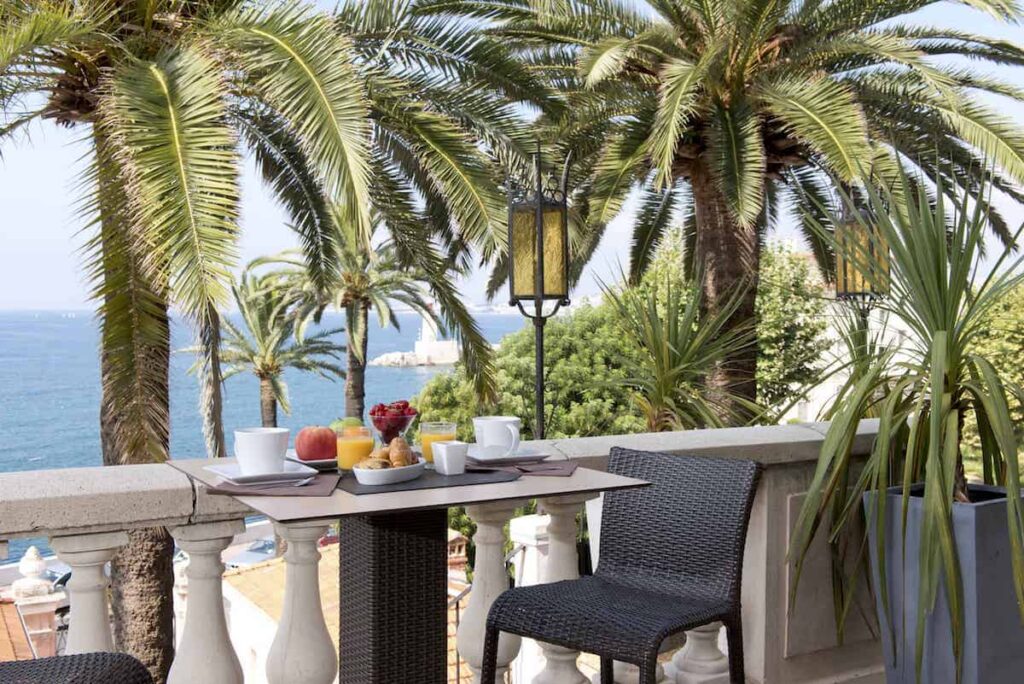Breakfast table with ocean view and palm trees.