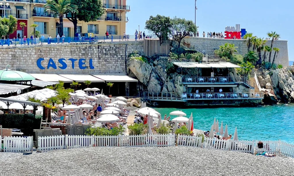 Pebble beach with umbrellas and cliffside restaurant