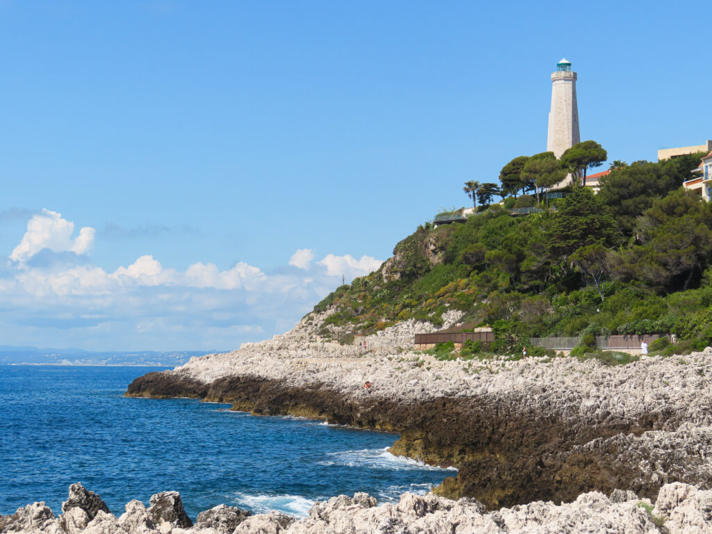 Lighthouse on rocky coastal cliff by sea
