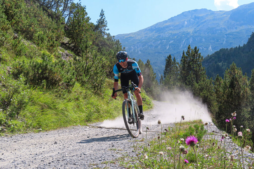 Cyclist on dusty mountain gravel trail